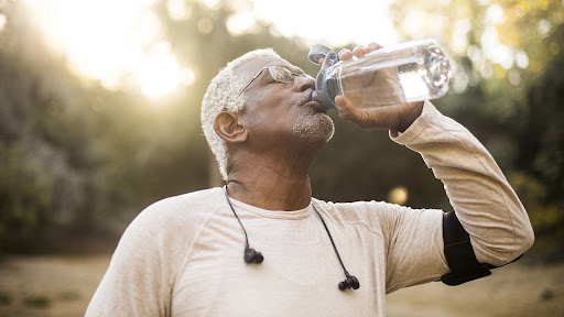 man staves off Dehydration Symptoms in Elderly by drinking water outside
