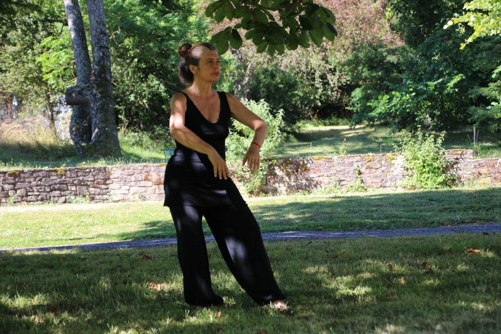 older woman practicing tai chi outside