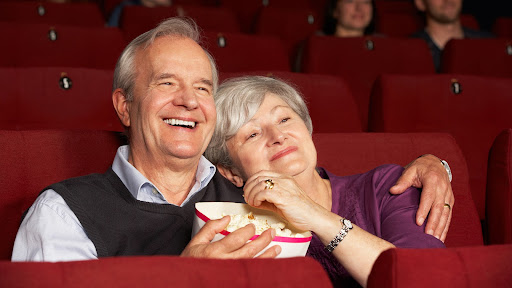 senior couple watching movies about retirement in the theater with popcorn