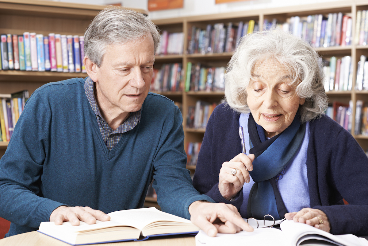 Mature Student Working With Teacher In Library